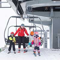 Kids getting off a lift with their ski instructor