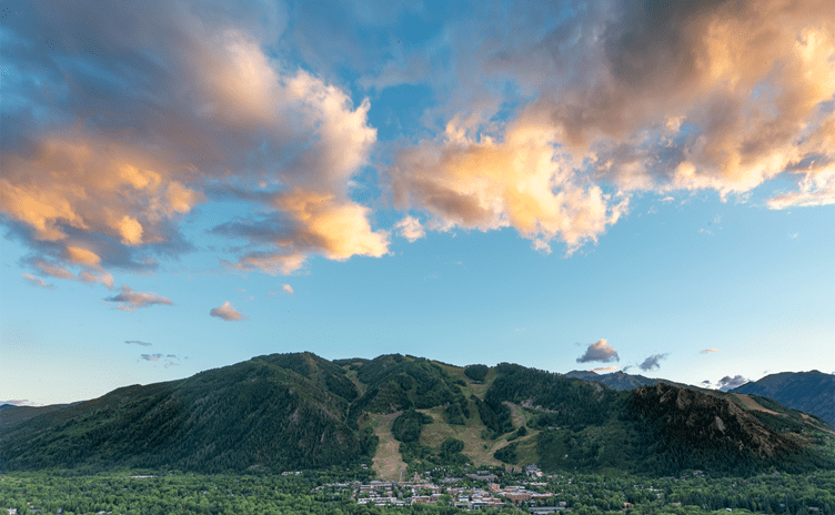 Wide view of the town of Aspen during June and the mountain behind it, beautiful su set and very green landscape. 