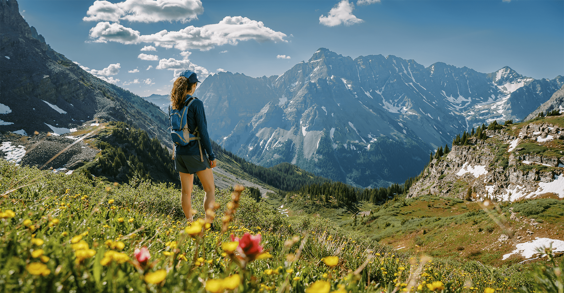 Hiker stands and takes in the view in a field of wildflowers 