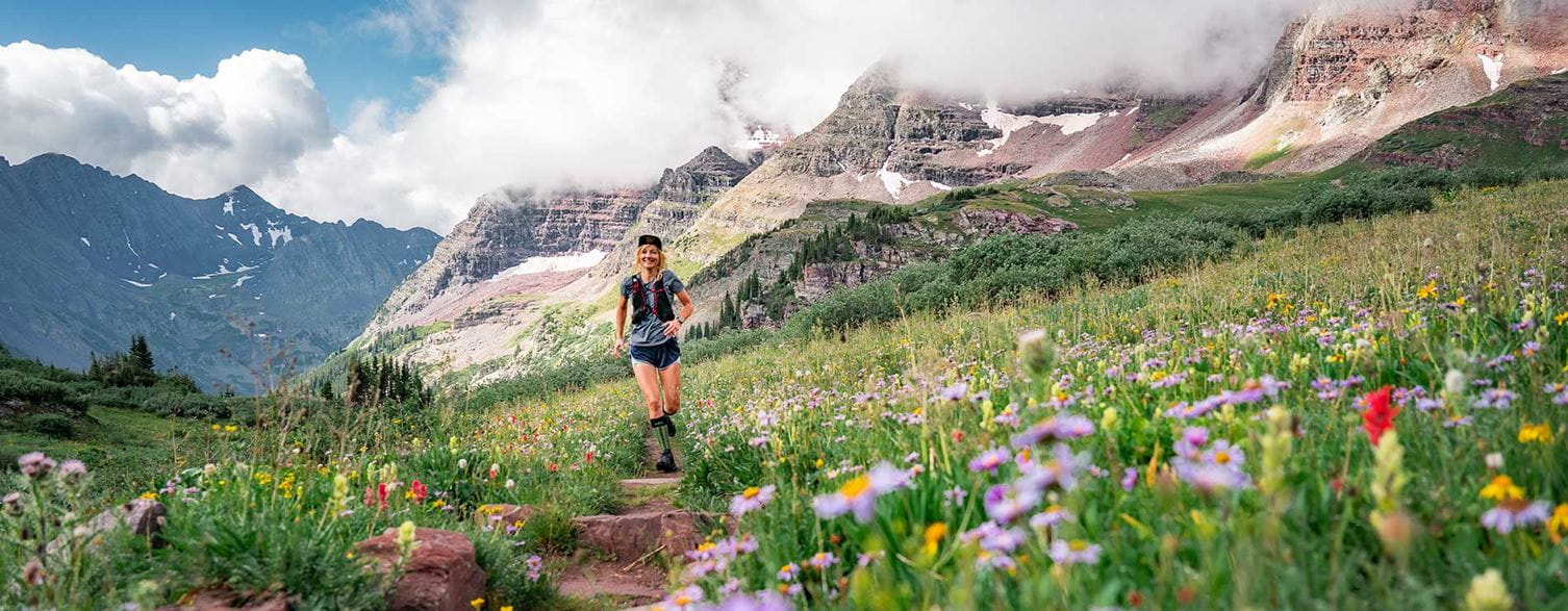 Inside Aspen Snowmass - Summer - Woman walking through alpine wildflower meadow in Colorado