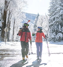 Two skiers walking down the sidewalk in Aspen Colorado.