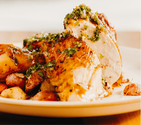 Plate with chicken and potatos, dressed in green pesto sauce