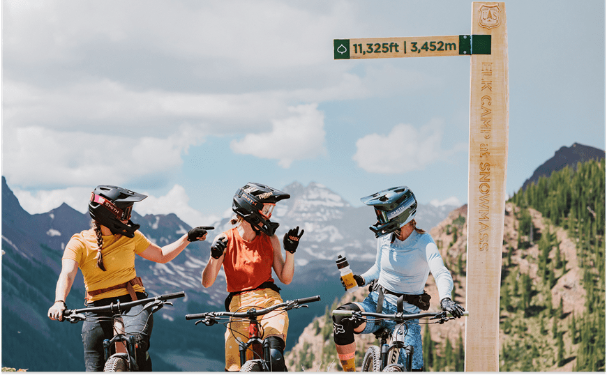 3 People on bikes with a view behind Snowmass