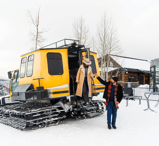Couple exiting a snowcat for dinner at The Cabin on Snowmass