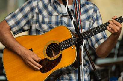 close up of man playing guitar, atop of aspen mountain in the summer