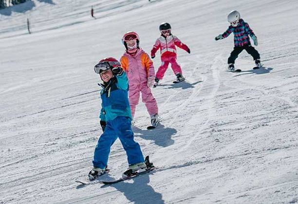 A row of kids learns to ski at Aspen Snowmass
