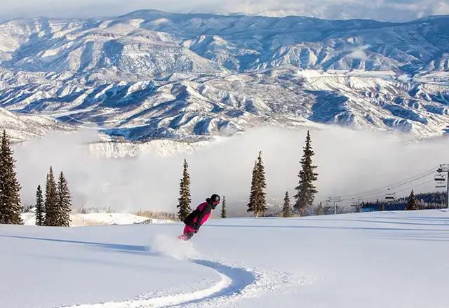 Snowboarder enjoys perfect powder and a mountain view at Aspen Snowmass
