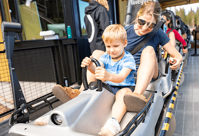 a child and his mother get ready to ride the alpine coaster