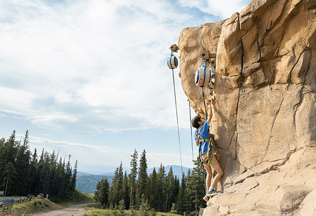 a child scales the rock wall at camp aspen Snowmass