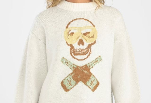 White sweater with skull and champagne cross bones on it