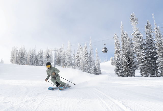 single skier carves under the aspen gondola during first tracks