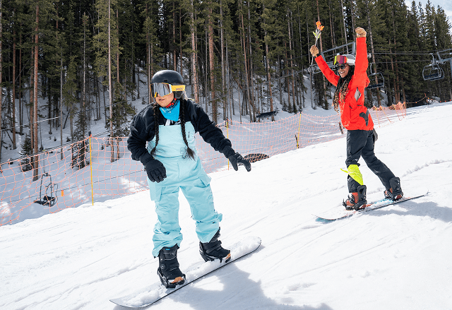 aspen snowmass ski pro cheers on their student as she snowboards down the bunny hill