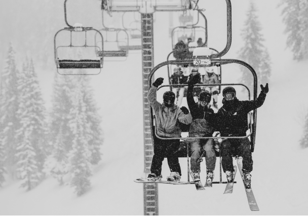 Three skiers on a lift on a snowy day at aspen mountain