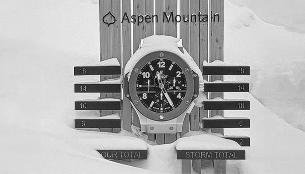 black and white image of snow stake with snow drifting up and over snow stake