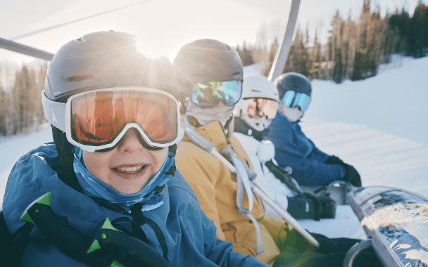family smiles on lift on the way up to the top of snowmass
