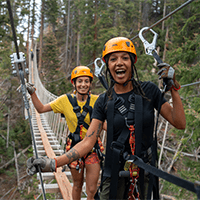 Two women enjoy the zip line course in lost forest