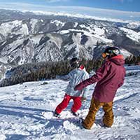 Snowboarder learning to read a run with a snowboard pro at Aspen Snowmass
