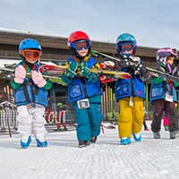 Kids carrying their skis to a lesson