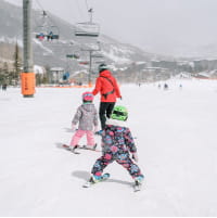 Two kids following a ski pro during a lesson on Snowmass Mountain