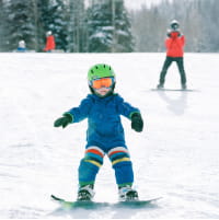 Young boy snowboarding on a mountain in a blue outfit