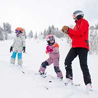 Ski instructor applauding kids learning to ski