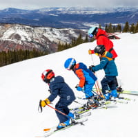 3 kids ready to ski down a slope with their instructor