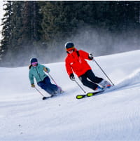 A ski pro guiding a guest down the mountain slope