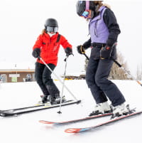 Person getting a ski lesson on a winter day at a mountain resort