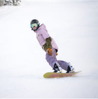 Person in purple outfit snowboarding on a ski slope
