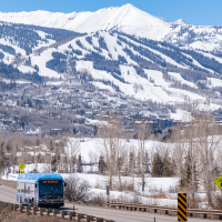 Bus on highway with snowmass in the distance