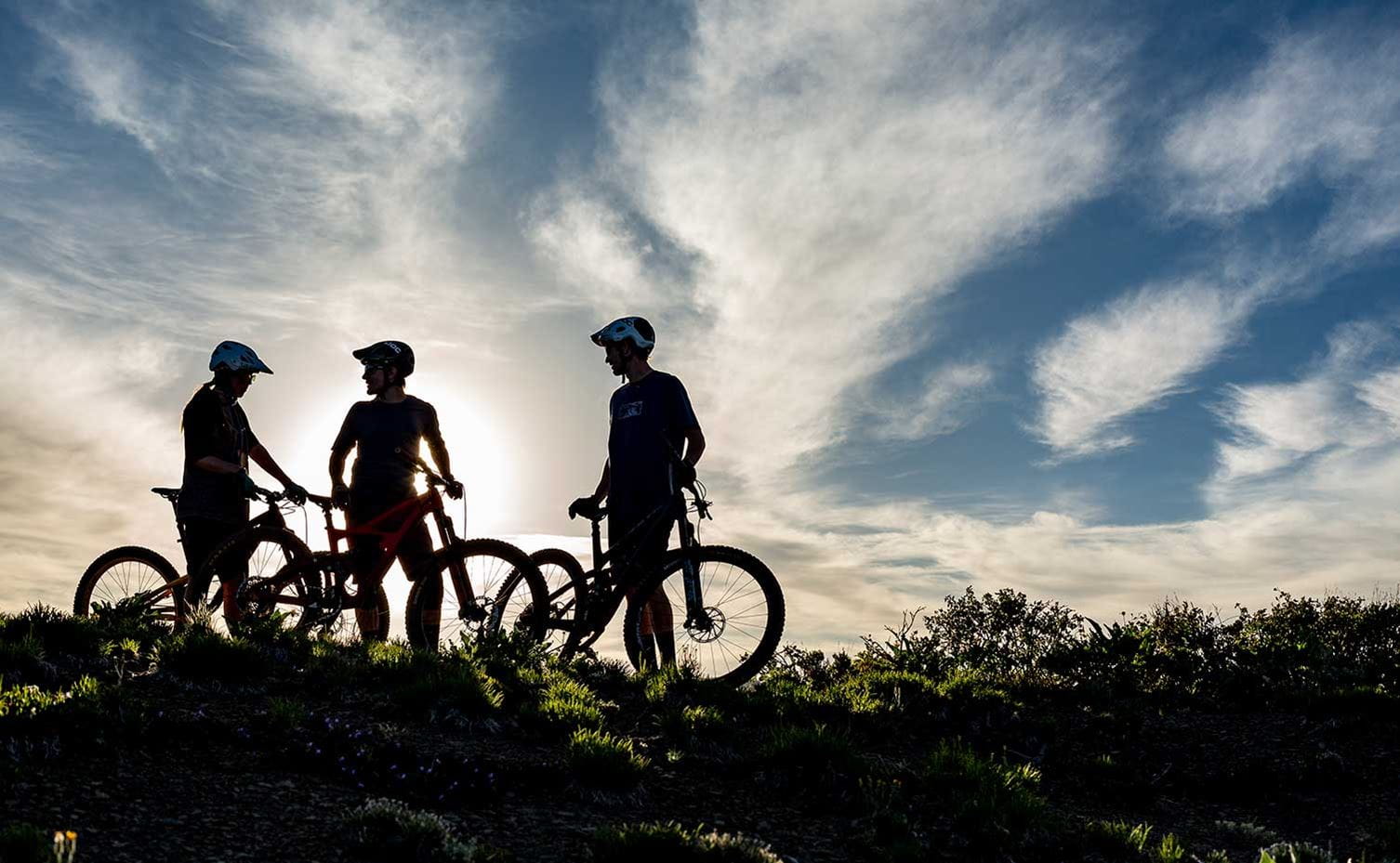 Three cross-country mountain bikers break during sunset near Aspen, Colorado