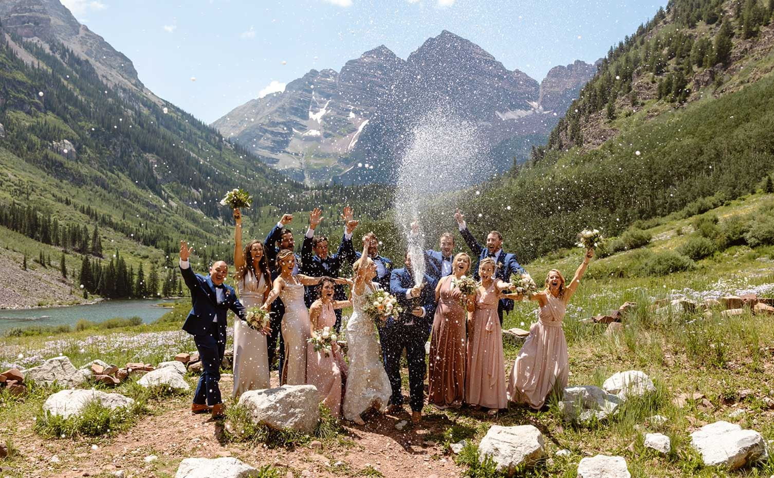 Wedding party pops champagne in front of Maroon Bells.