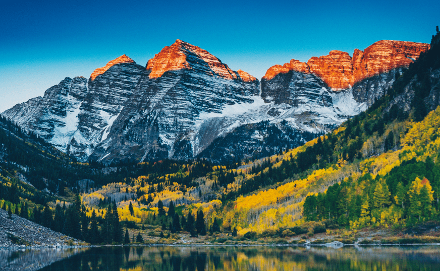 a mountain range with trees and a lake
