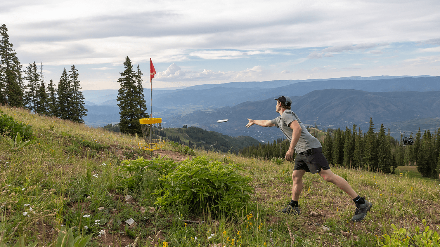 Man plays frisbee golf on Lost Forest, looking out above the valley
