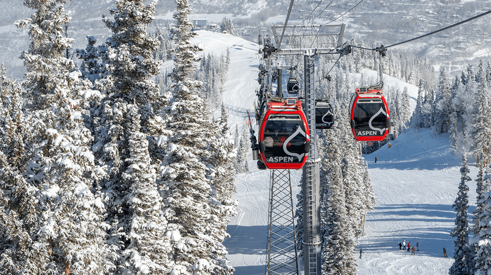 Two gondola cars move up the mountain on Aspen Mountains Silver Queen Gondola on a snowy day