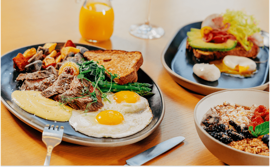 Plates of Brunch food like eggs, toast and orange juice