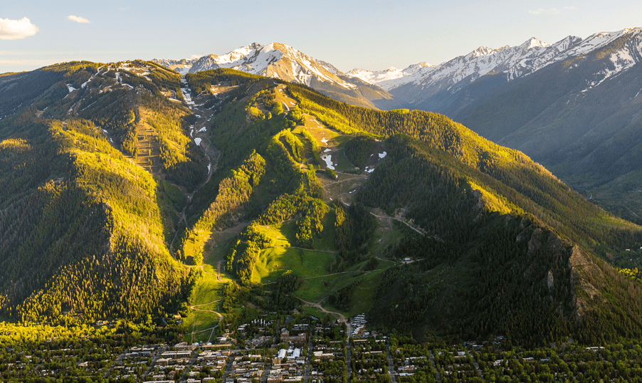 Birdseye view of Aspen Mountain in the spring, green runs with a little leftover snow at the peak