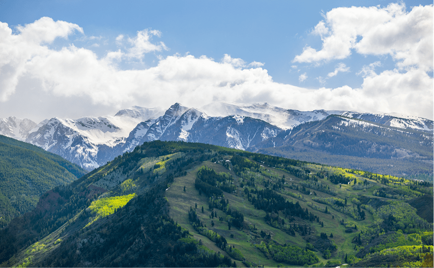 Aerial view of Buttermilk mountain, in summer, green ski runs and snowy peaks in distance