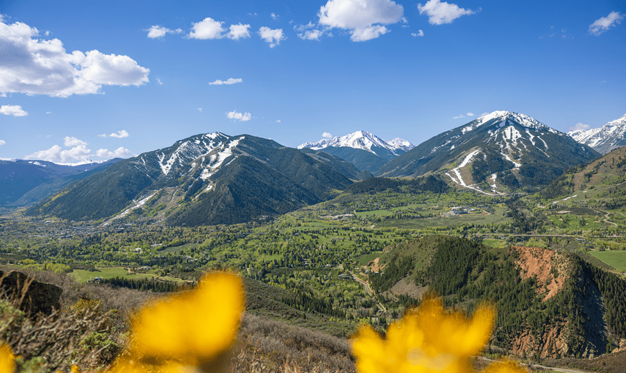 long shot of buttermilk mountain, green hills with a little remaining snow on the ski runs