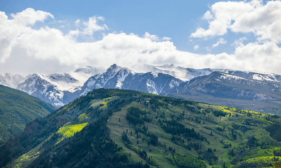Buttermilk on an early summer day, green trees line the ski runs, now covered in grass, under blue skies