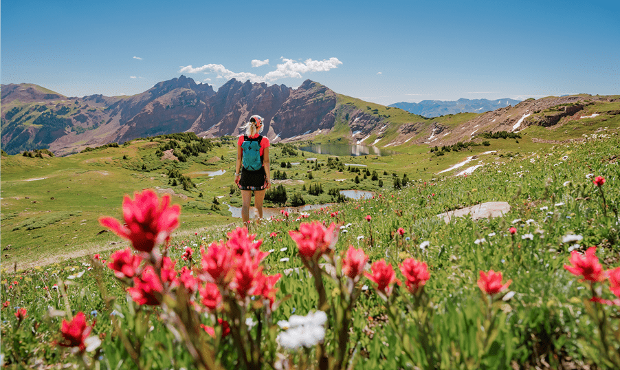 woman hiking in field with flowers in the snowmass wilderness