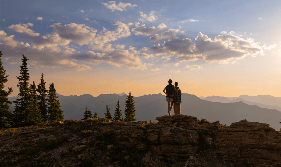 Sunset over aspen mountain with two hikers at the top