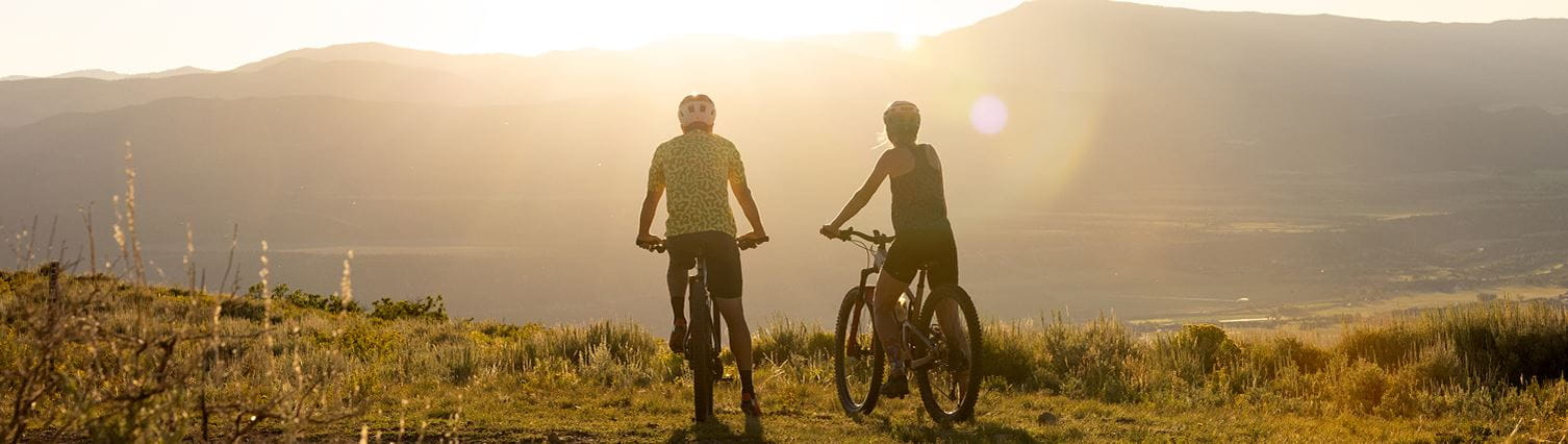couple sits on bikes atop snowmass