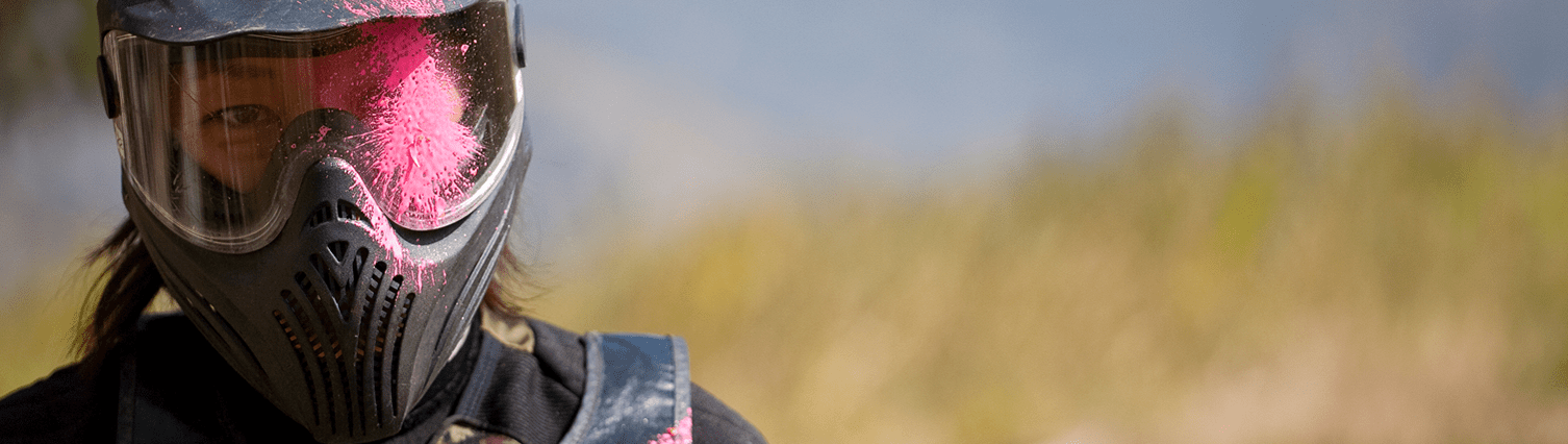 Close up of person playing paintball, purple paint on their goggles