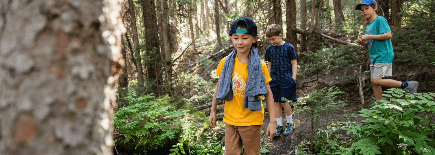 Young boy walks through forest at camp aspen snowmass
