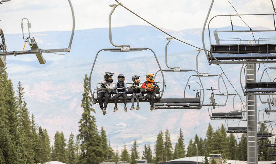 Elk Camp lift, four young boys ride up, their bikes in the chair ahead of them, as they go to the snowmass bike park