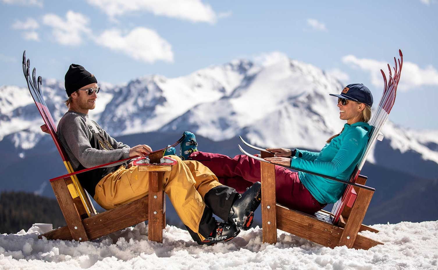 A couple enjoys apres ski drinks on top of a mountain
