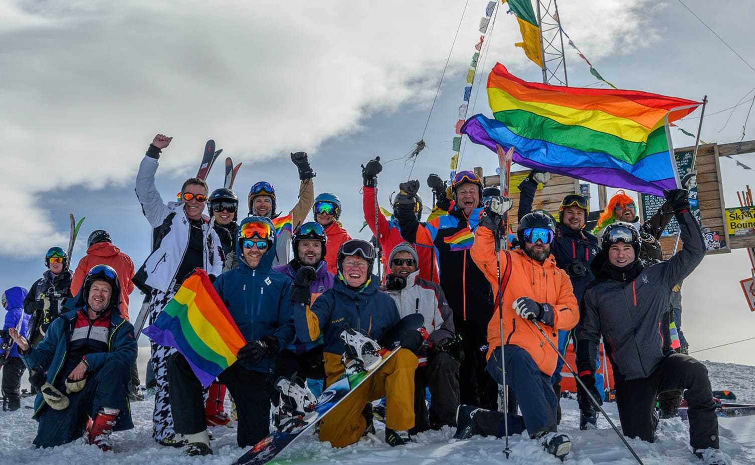 Group gathered with LGBTQ+ flag at the top of Highland Bowl. 