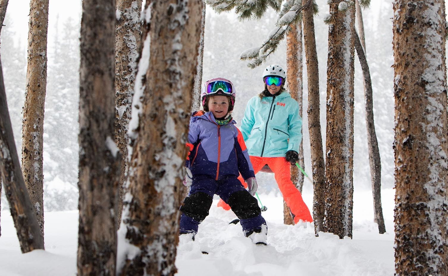 Child and parent skiing through the trees in Aspen Colorado. 