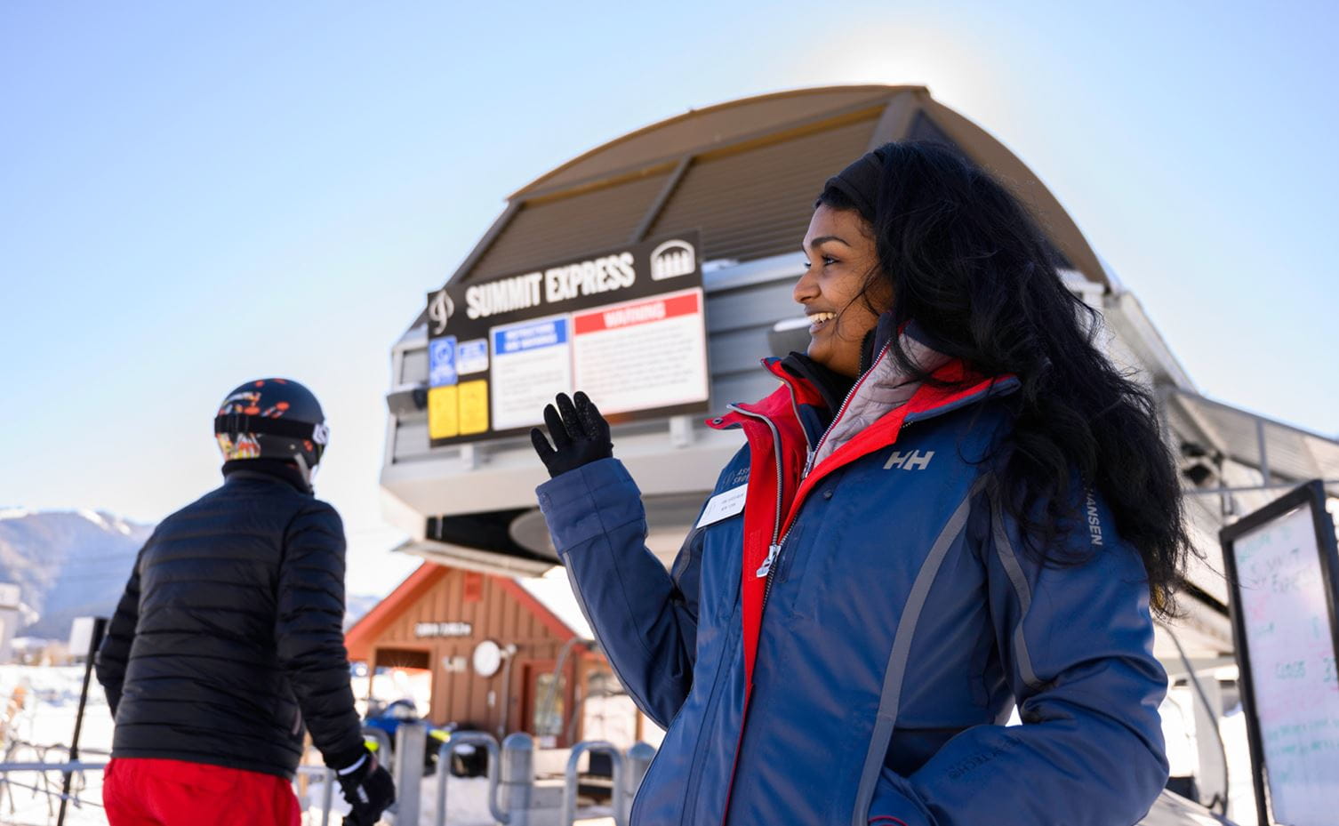 An employee of Aspen Skiing Company greets people at a lift